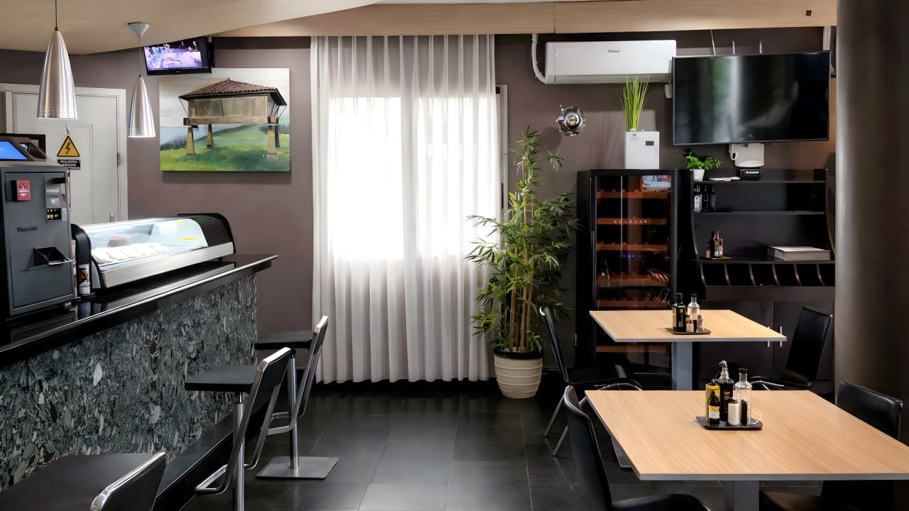 Barra de la cafetería con taburetes y vitrina en el Hotel Ruta Romana de Sagunto