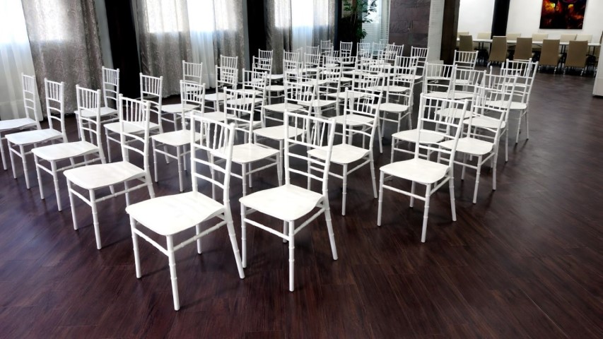 Sillas Chiavari blancas preparadas para ceremonia de boda en la carpa