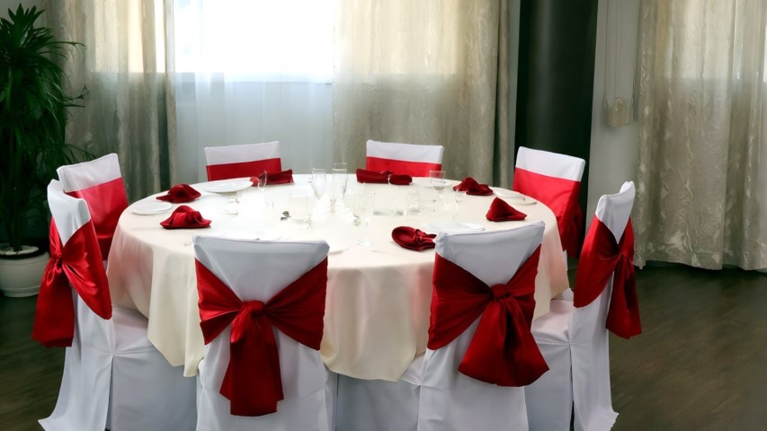 Mesa redonda elegantemente decorada con lazos de satén rojos para boda