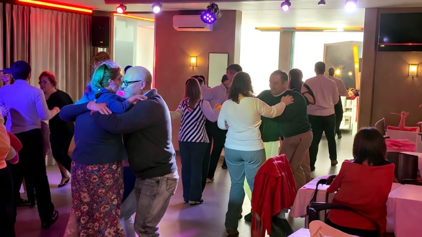 Parejas bailando lento en ambiente íntimo con iluminación de colores