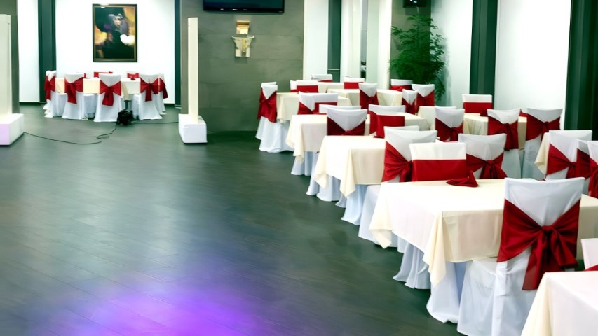 Sala completa con mesas decoradas con lazos rojos e iluminación LED en el suelo
