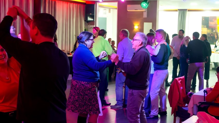 Múltiples parejas bailando en el salón de eventos con iluminación de colores