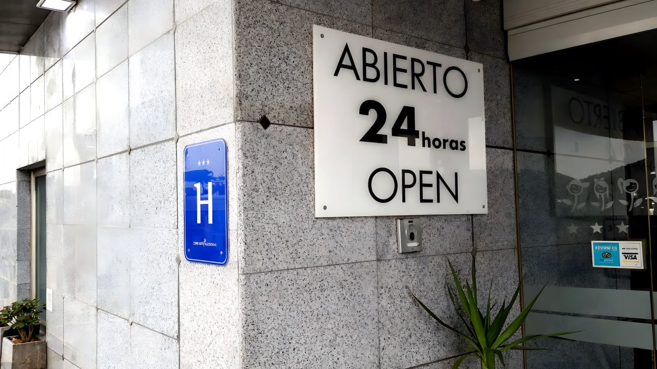 Cartel ABIERTO 24 horas OPEN en la entrada del hotel