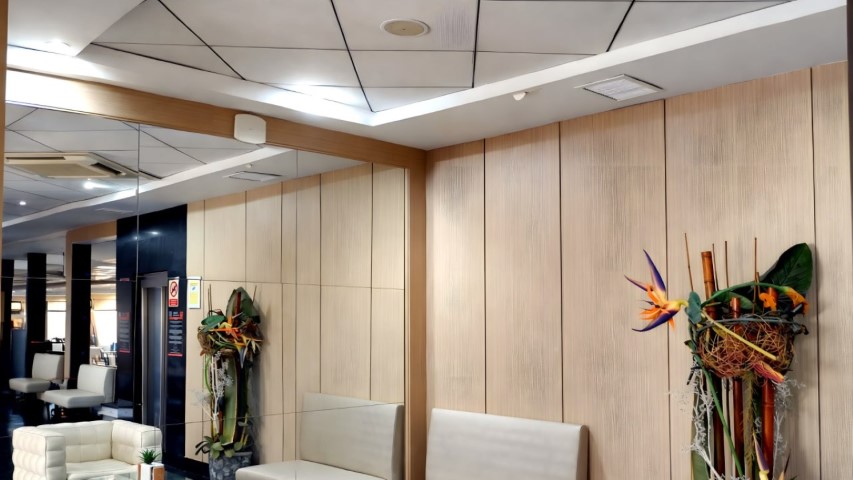 Sala de espera del hall con paneles de madera clara y sofás blancos