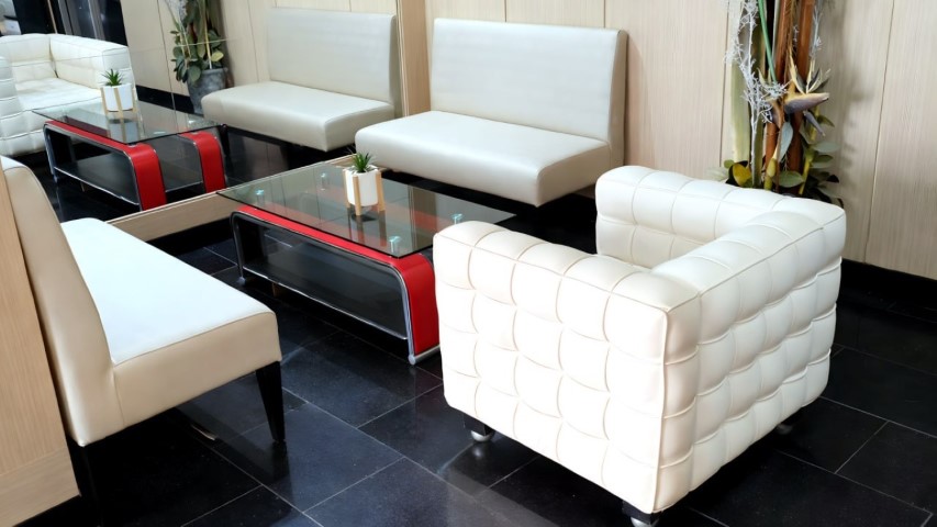 Zona de asientos del hall con mesas de cristal y detalles rojos