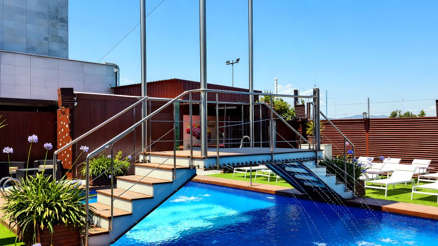 Deck de madera y lado opuesto de la piscina del Hotel Ruta Romana